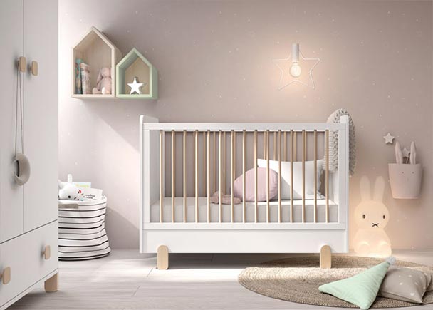 Dormitorio para bebés con una cuna con ruedas de barandilla deslizante y cajón inferior